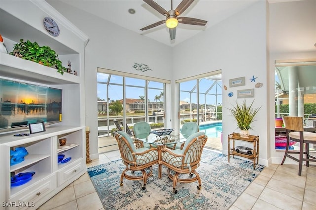 dining space with a high ceiling, a water view, light tile patterned floors, and ceiling fan