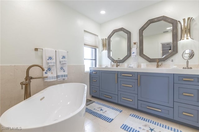 bathroom with tile patterned flooring, vanity, tile walls, and a bathing tub