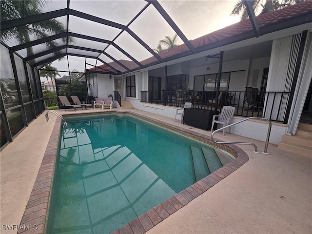 pool at dusk with a patio area and glass enclosure