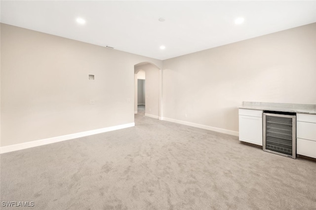 unfurnished living room featuring light colored carpet and wine cooler