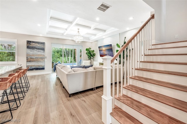 living room with light wood finished floors, visible vents, coffered ceiling, beamed ceiling, and stairs