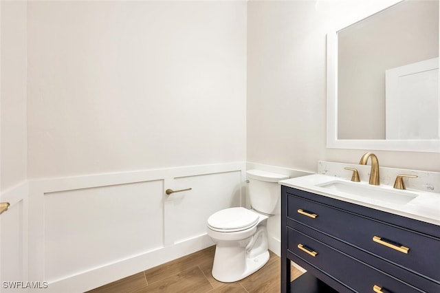 bathroom with wood-type flooring, vanity, and toilet