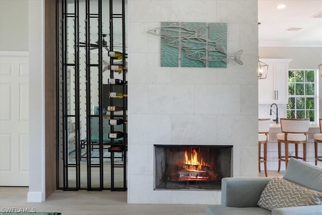 interior space with a tiled fireplace, crown molding, hardwood / wood-style flooring, and sink