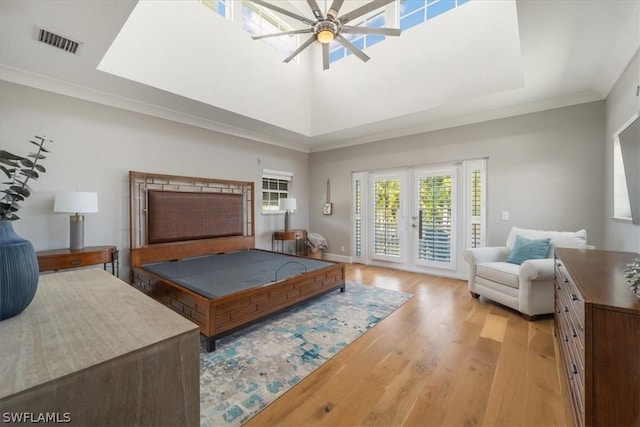 bedroom featuring french doors, a towering ceiling, ceiling fan, access to exterior, and light hardwood / wood-style floors