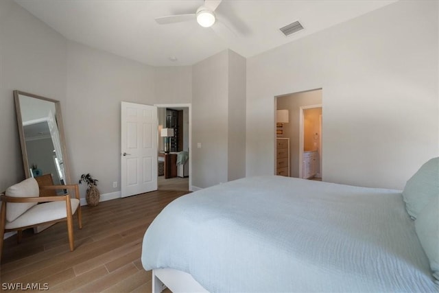 bedroom featuring wood-type flooring, a towering ceiling, ensuite bathroom, and ceiling fan