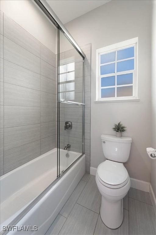 bathroom with enclosed tub / shower combo and toilet