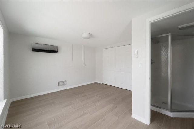 interior space with a closet, a wall unit AC, and light hardwood / wood-style flooring