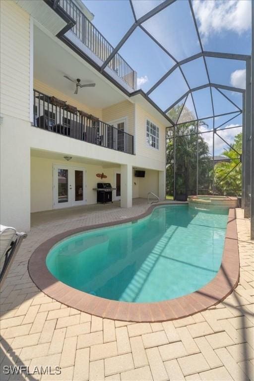 view of swimming pool with french doors, a patio, ceiling fan, and glass enclosure