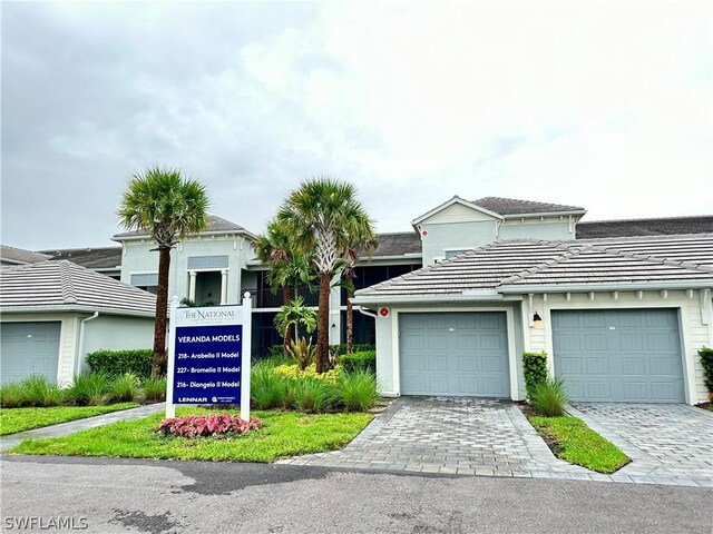6070 National Blvd Unit 215, Ave Maria, FL 34142 - view of front facade featuring decorative driveway, a tile roof, and an attached garage