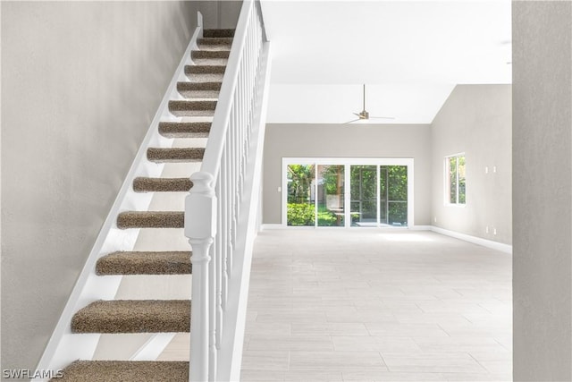 staircase featuring high vaulted ceiling and ceiling fan