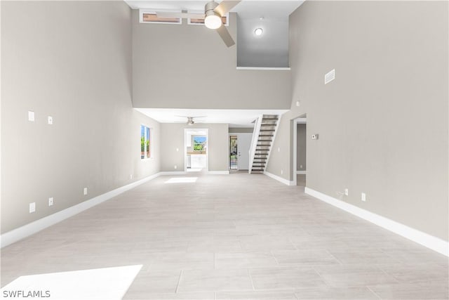 unfurnished living room with ceiling fan and a high ceiling