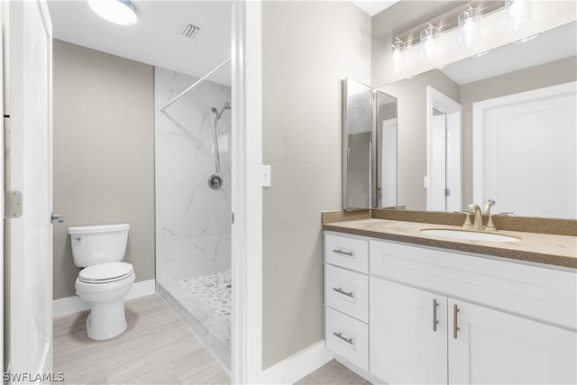 bathroom with a tile shower, vanity, and toilet