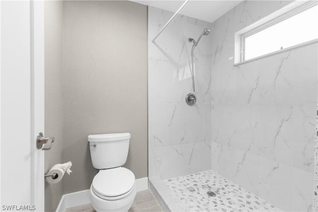 bathroom featuring a tile shower and toilet