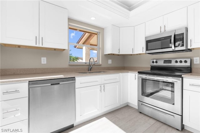 kitchen featuring sink, crown molding, white cabinetry, and stainless steel appliances