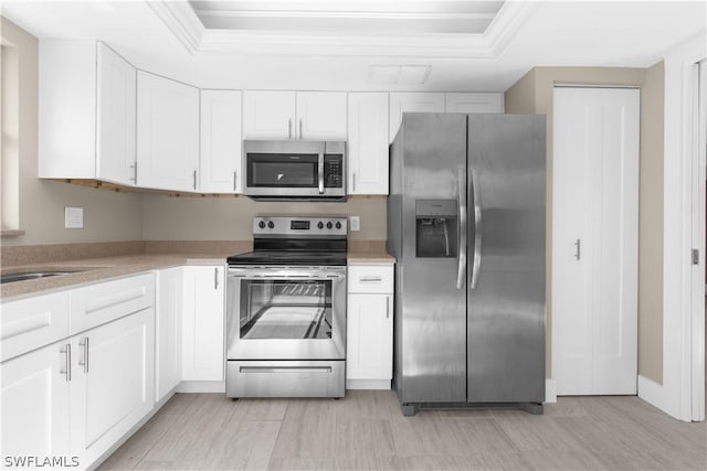 kitchen featuring appliances with stainless steel finishes, white cabinetry, ornamental molding, and sink