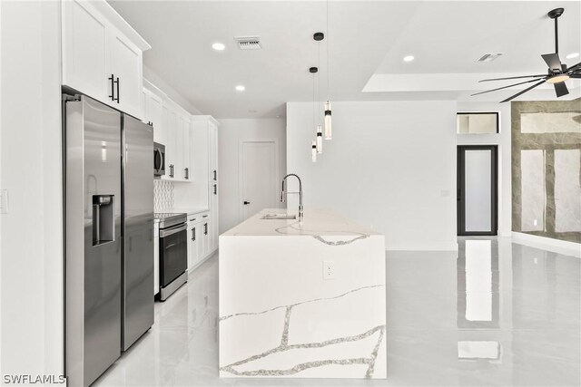 kitchen featuring appliances with stainless steel finishes, pendant lighting, white cabinetry, sink, and light stone counters