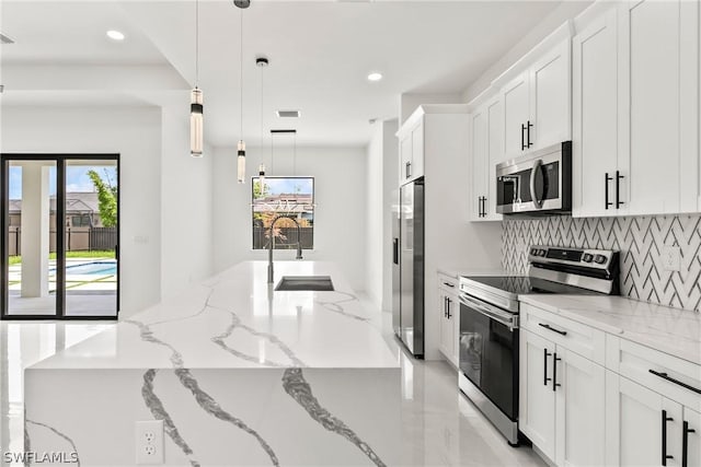 kitchen featuring white cabinetry, appliances with stainless steel finishes, sink, and hanging light fixtures