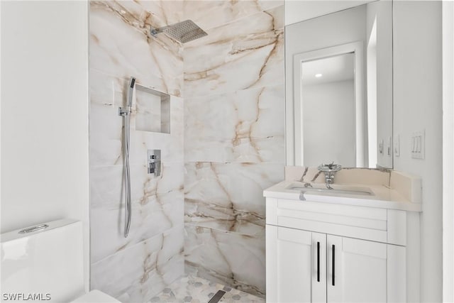 bathroom with tiled shower, vanity, and toilet