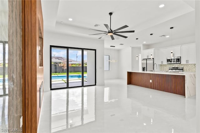 kitchen with pendant lighting, sink, white cabinetry, backsplash, and stainless steel appliances