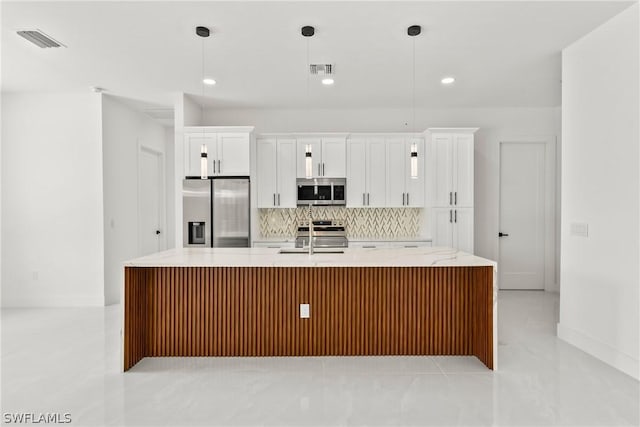 kitchen featuring white cabinetry, stainless steel appliances, a center island with sink, and pendant lighting