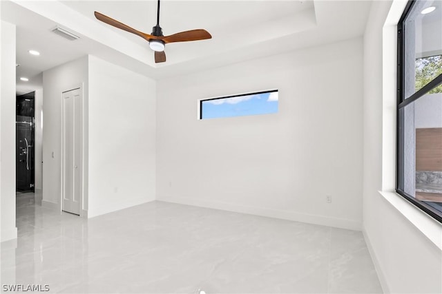 spare room featuring a tray ceiling and ceiling fan