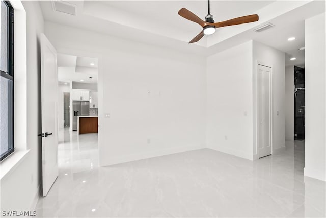 unfurnished room featuring ceiling fan and a raised ceiling