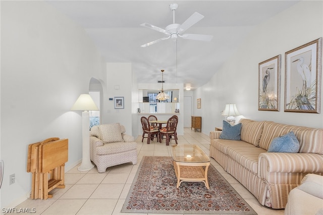 living room featuring ceiling fan with notable chandelier, light tile patterned flooring, and vaulted ceiling