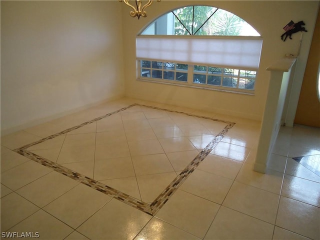 unfurnished room featuring a chandelier, baseboards, and light tile patterned floors