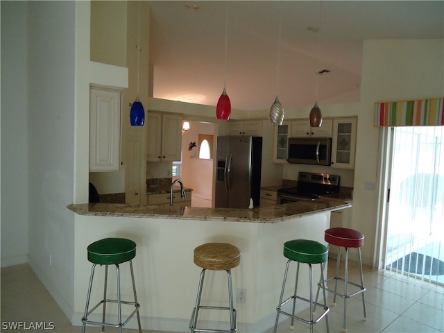 kitchen featuring pendant lighting, a breakfast bar, kitchen peninsula, stone counters, and appliances with stainless steel finishes