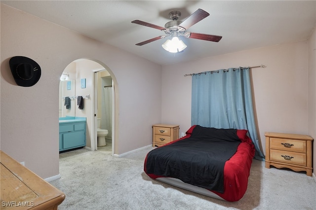 carpeted bedroom with ensuite bathroom and ceiling fan