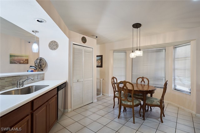 kitchen with light tile patterned floors, pendant lighting, decorative backsplash, sink, and dishwasher