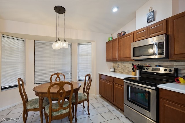 kitchen with appliances with stainless steel finishes, lofted ceiling, tasteful backsplash, and decorative light fixtures