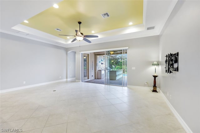 spare room featuring ceiling fan, visible vents, arched walkways, and a raised ceiling