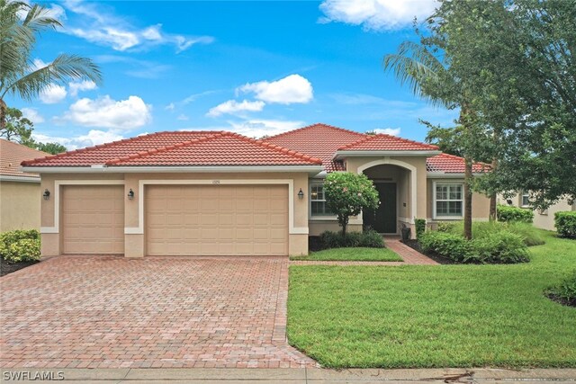 mediterranean / spanish-style home featuring a front lawn and a garage