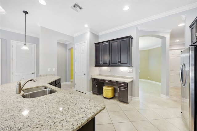 kitchen with arched walkways, light stone counters, a sink, visible vents, and freestanding refrigerator