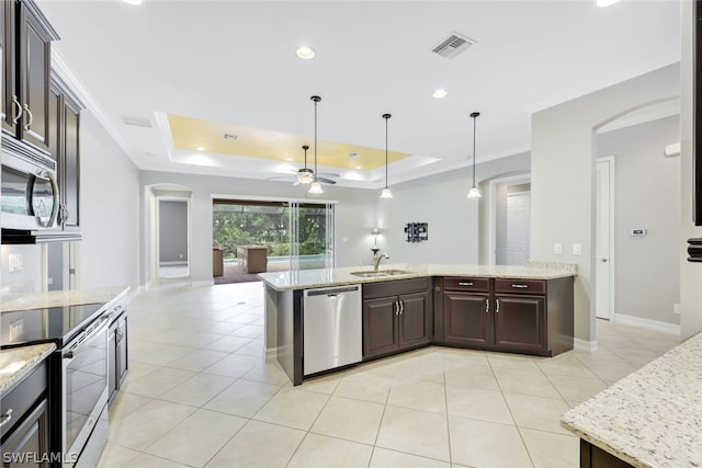 kitchen with a sink, visible vents, appliances with stainless steel finishes, a tray ceiling, and decorative light fixtures