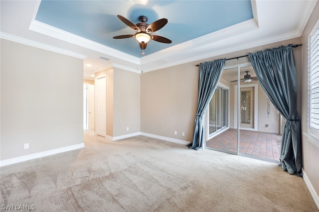 unfurnished room featuring a raised ceiling, light colored carpet, visible vents, ornamental molding, and baseboards