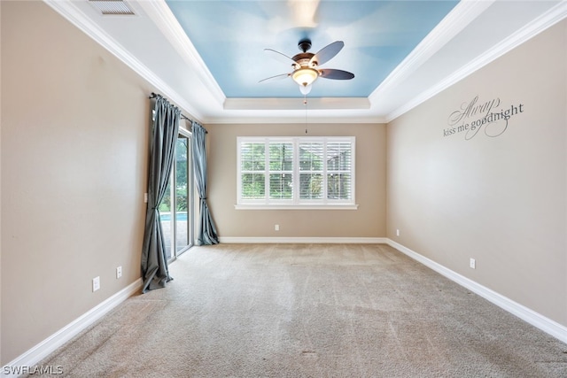 spare room featuring ornamental molding, a tray ceiling, visible vents, and baseboards