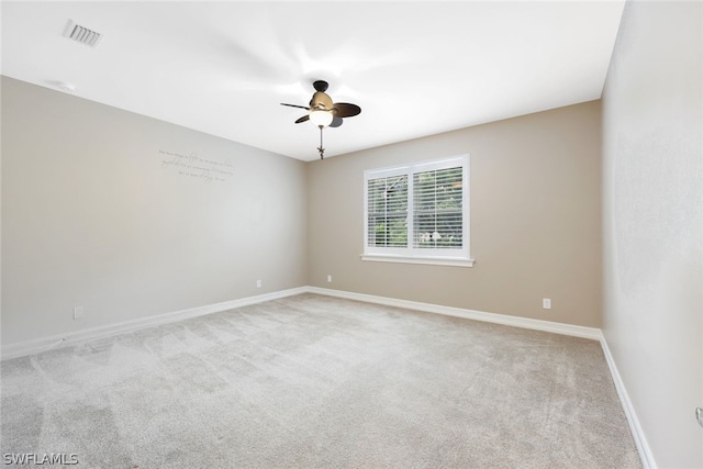 empty room with baseboards, light carpet, visible vents, and a ceiling fan