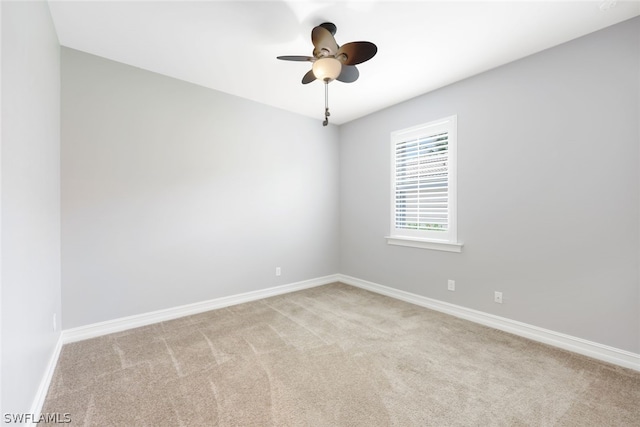 spare room featuring light carpet, a ceiling fan, and baseboards