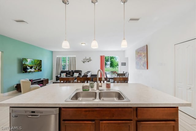 kitchen featuring stainless steel dishwasher, sink, hanging light fixtures, and a center island with sink