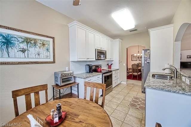 kitchen with sink, light tile patterned floors, light stone countertops, stainless steel appliances, and white cabinets