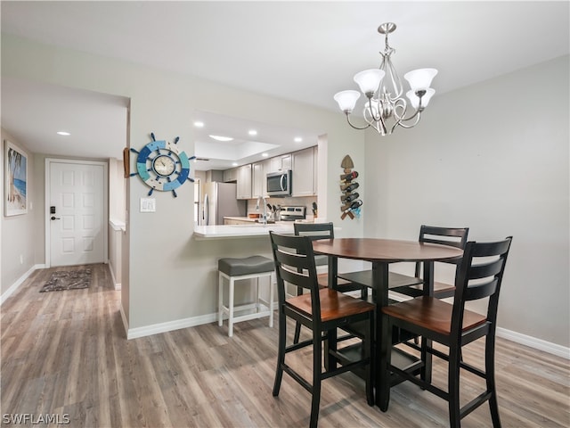 dining room with an inviting chandelier, sink, and light hardwood / wood-style flooring