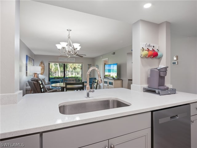 kitchen featuring a chandelier, light stone counters, sink, and stainless steel dishwasher