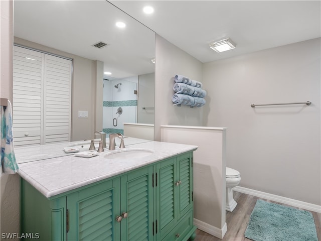 bathroom with tiled shower, vanity, hardwood / wood-style flooring, and toilet