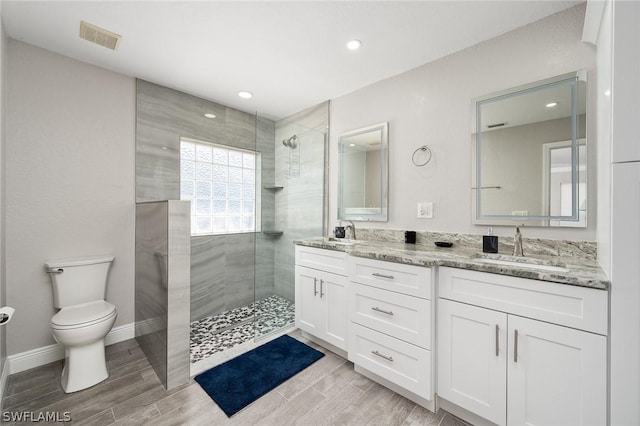 bathroom with a tile shower, vanity, and toilet