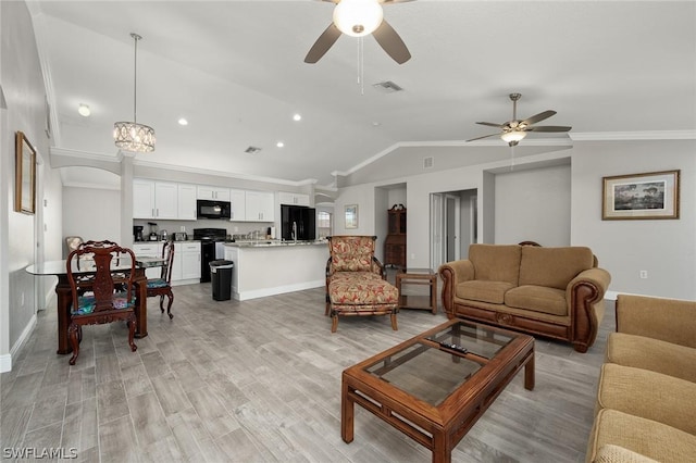 living room with lofted ceiling, crown molding, ceiling fan with notable chandelier, and light wood-type flooring