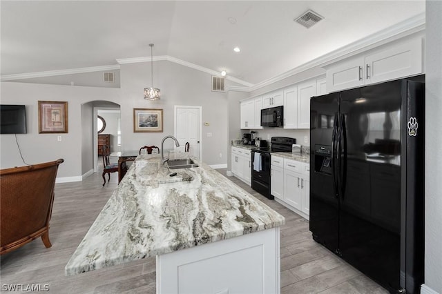 kitchen with lofted ceiling, black appliances, sink, an island with sink, and white cabinetry