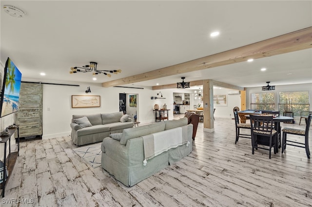 living room featuring beamed ceiling, a barn door, and light wood-type flooring