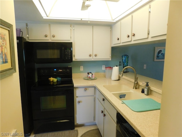 kitchen featuring white cabinets, a skylight, black appliances, and sink